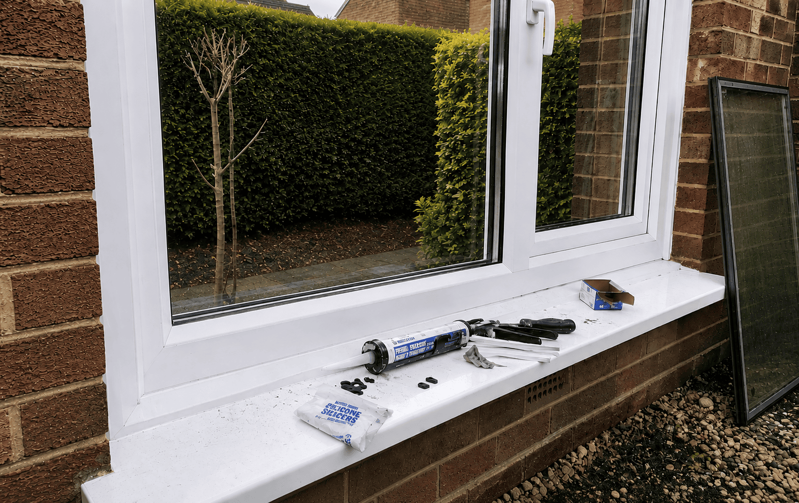 Glass Repairs in Ely with glazing tools beside a white uPVC window during sealed unit replacement.