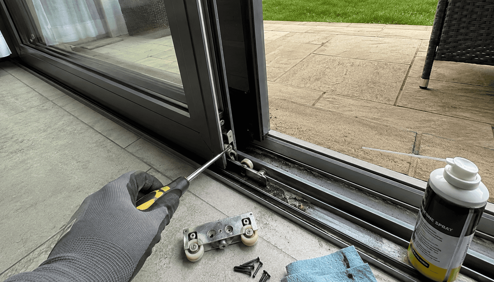Glass Repairs in Ely showing a sliding glass door track and roller repair with hand tools.