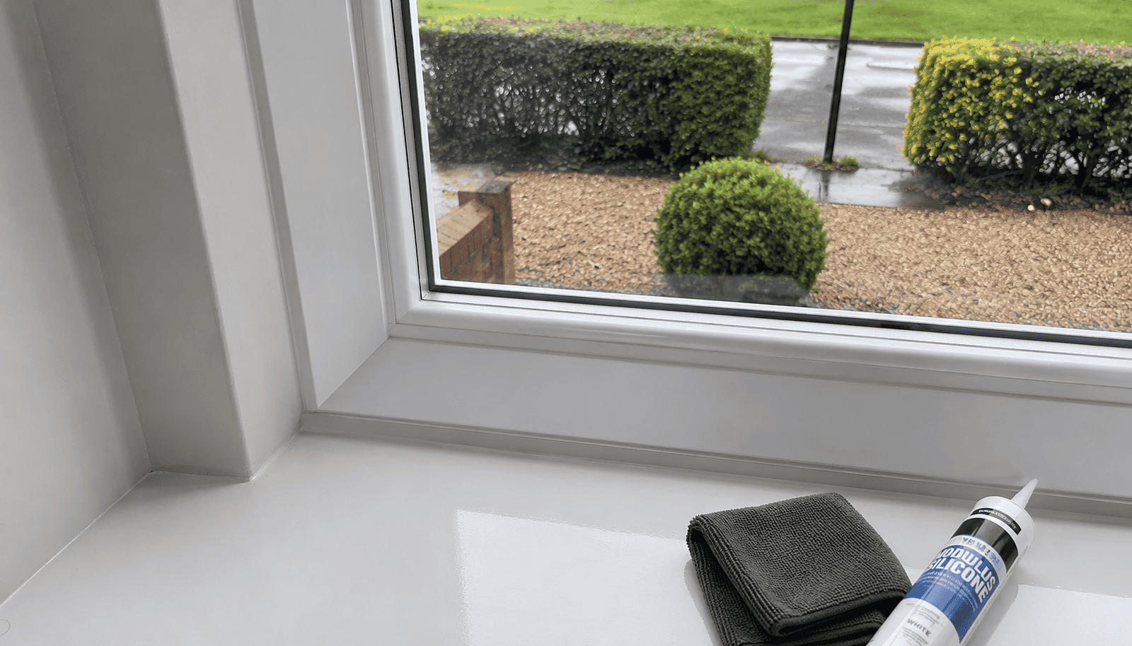 Glass Repairs in Ely showing a finished uPVC window seal with silicone and cleaning cloth.
